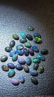 Group of oval cabochon Ethiopian black opals on dark surface