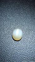 Top view of the moonstone cabochon on black textured background