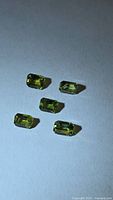 Five emerald-cut yellow-green sapphires on white background