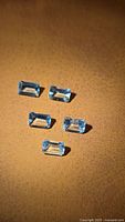 Five emerald-cut light blue aquamarines on leather surface