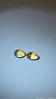 Two pear-shape golden citrine cabochons on neutral background