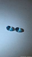 Two seafoam blue pear-cut zircons on neutral background