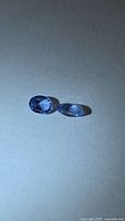 Pair of loose blue-violet tanzanites, oval and marquise cuts, on neutral background
