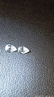 Two pear cut colorless zircons on black surface