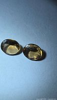 Two oval faceted yellow-brown tanzanite gemstones on light background