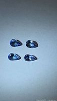 Top view of four pear-cut tanzanites on neutral background