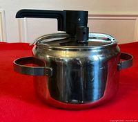 Side view of stainless pressure cooker showing side handles and lid assembly