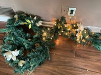 Lit evergreen garland section showing clear lights and gold/white decorations