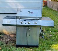 Front view of stainless Char-Broil 3-burner grill with side burner lid and right shelf