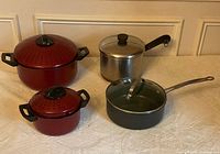 All four pots arranged on surface showing relative sizes and lids