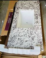Top view of Bianco Antico vanity top inside box showing rectangular sink and faucet holes