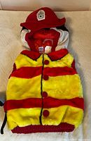 Front view of infant firefighter vest with hat placed on top, showing overall design and colors