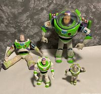 Group shot of four Buzz Lightyear figures showing relative sizes and helmet presence