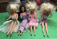 Group shot of four 12-inch dolls seated on green surface