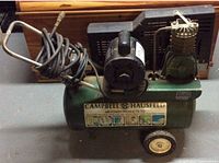 Full view of Campbell Hausfeld air compressor on wheels with hose