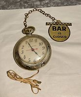 Full view of Spartus clock with chain and Bar Is Closed sign, power cord visible