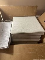 Open box showing stack of white textured ceiling tiles