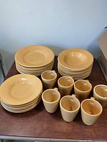 Full set of plates, bowls and mugs arranged on table