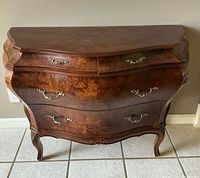 Front view of three-drawer curved French Provincial cabinet showing burl veneer, brass pulls, cabriole legs.