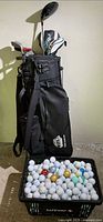 Full view of golf bag, clubs, crate of golf balls