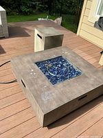 Full view of metal square fire pit on deck with cube cover