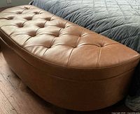 Top view of caramel vinyl tufted bench beside bed