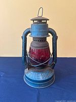 Front view of blue Dietz Little Wizard lantern with red globe