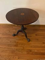 Full view of mahogany round pedestal table on hardwood floor