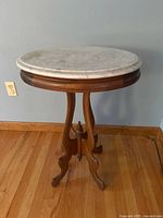 Side view of one marble-top side table showing marble surface and walnut pedestal base