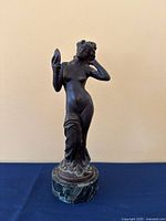 Front view of the metal female nude sculpture on marble base