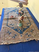 Full view of worn tribal table cover with dolls and vase on top