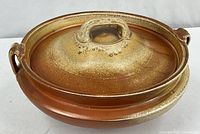 Side view showing full casserole with lid and one handle