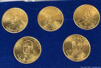 Five gold-tone presidential coins in blue lined tray