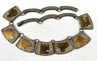 Full view of necklace showing eight stone and brass inlay plaques linked by curved silver bars