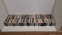 Full row of over 90 cassette tapes lined on shelf showing spines