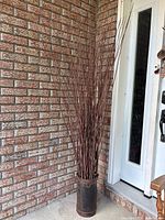 Full view of branches in pail against brick wall