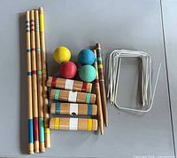 All croquet components laid out: mallet handles, heads, balls, stakes, wickets