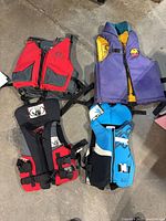 Four life jackets laid flat showing front designs and colours