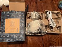 Open box with PartyLite branding showing warmer, cord and inserts