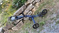 Full view of folded blue Sun Mountain three-wheel golf push cart showing frame and wheels