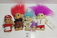 Front view of five troll dolls showing sizes, outfits, hair colors