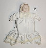 Front view of porcelain baby doll wearing satin gown and bonnet