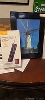 Detector box front beside black picture frame camera displaying windmill photo