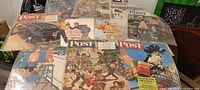 Overview of all eleven Saturday Evening Post covers spread on table