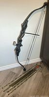 Full view of Oregon crossbow resting against wall with eight arrows on floor