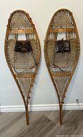 Front view of both wooden snowshoes showing full length and bindings