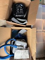 Two boxes containing DonJoy black cold therapy unit with pad and Breg grey unit with blue hoses and pads