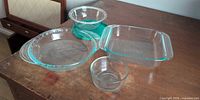 All Pyrex glassware on table: square dish, pie plate, mixing bowl, custard cup, teal lid