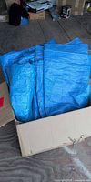 Box containing folded blue tarps