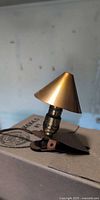 Side view of lamp showing conical copper shade, brass socket, spring clip base